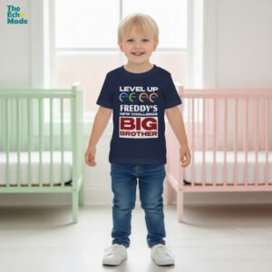 Toddler boy wearing personalized Level Up Big Brother navy t-shirt standing between two cribs